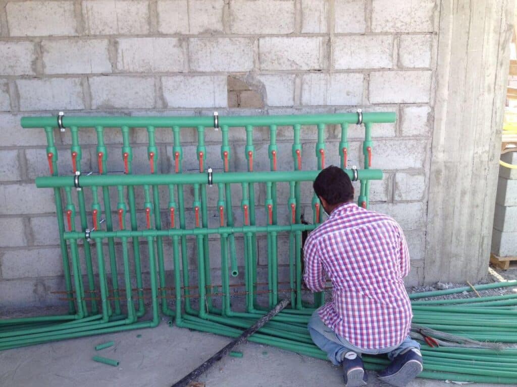 سباك يعمل ليلاً على إصلاح صمام مياه رئيسي خارج منزل في الكويت تحت إضاءة مركزة