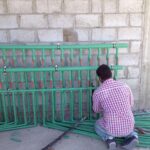 سباك يعمل ليلاً على إصلاح صمام مياه رئيسي خارج منزل في الكويت تحت إضاءة مركزة